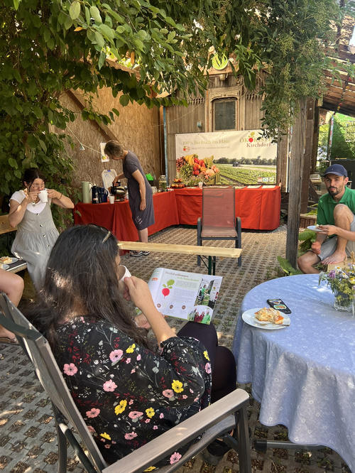 KI-generierte Beschreibung: Menschen genießen Essen und Getränke im Freien unter Bäumen.