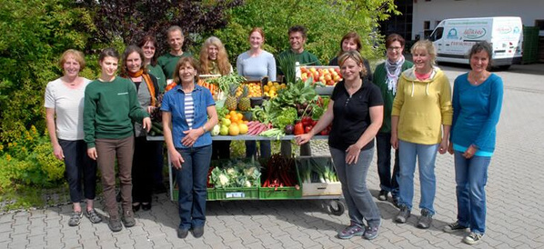 KI generiert: Eine Gruppe von Menschen posiert mit frischem Obst und Gemüse im Freien.