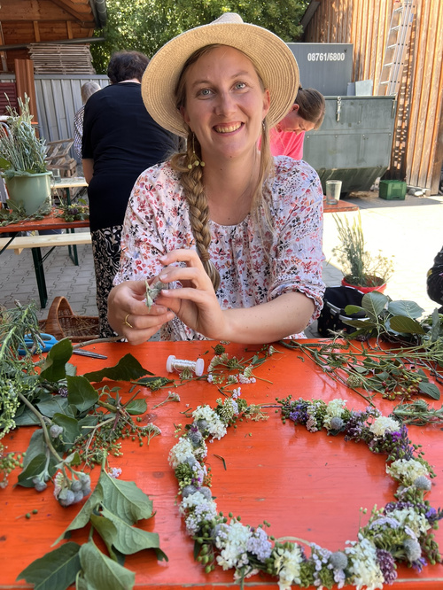 KI-generierte Beschreibung: Eine Frau hält einen Blumenstrauß vor einem Marktstand.