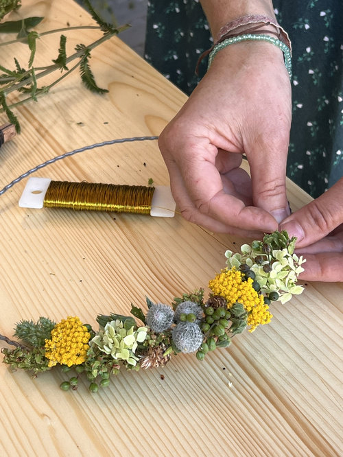 KI-generierte Beschreibung: Eine Person hält einen geflochtenen Korb mit Blumen.