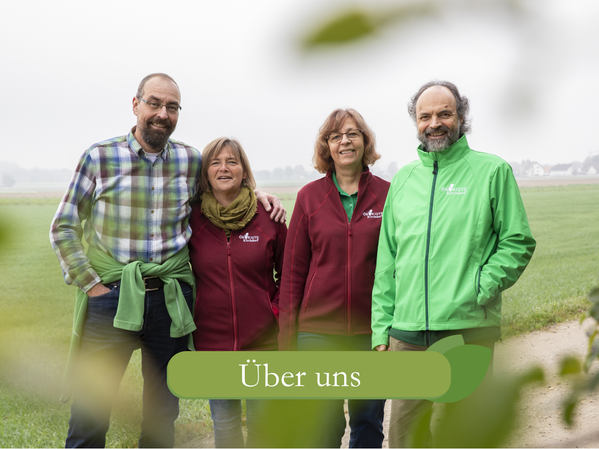 KI generiert: Vier Personen stehen in einer ländlichen Umgebung. Text: "Über uns".