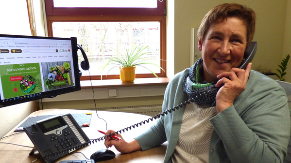 KI generiert: Eine lächelnde Person telefoniert im Büro. Auf dem Bildschirm: "NEUKUNDEN AKTION".