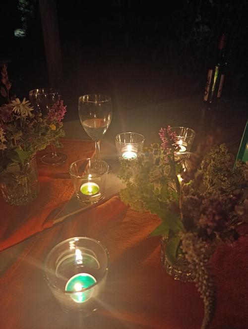 KI-generierte Beschreibung: Hauptinhalt: Kerzen und Blumen auf Holztisch.
