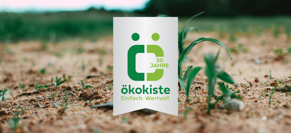 KI generiert: Ein Feld mit der Aufschrift "ökokiste Einfach. Wertvoll." über grünen Pflänzchen im Vordergrund.
