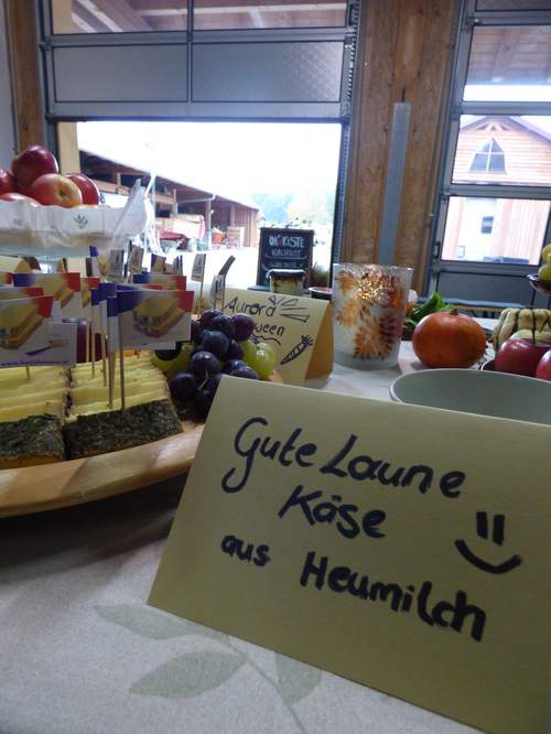 KI-generierte Beschreibung: Auslage mit Käsesorten und Text "Gute Laune Käse aus Heumilch".