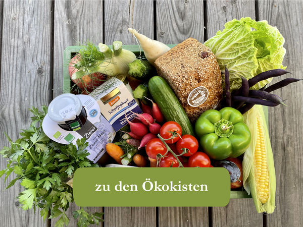 KI generiert: Eine Kiste mit frischem Gemüse, Brot und Milchprodukten. Text: "zu den Ökokisten".