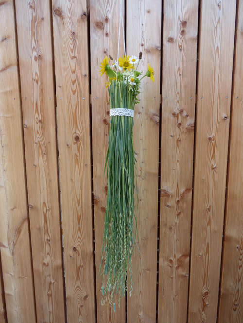 KI-generierte Beschreibung: Blumenstrauß in grüner Vase vor Holzvertäfelung.
