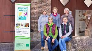 KI generiert: Fünf Personen posieren neben einem Banner mit der Aufschrift "Bergland-Kräuter" vor einem Gebäude.