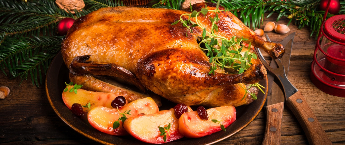 KI generiert: Ein gebratener Gänsebraten auf einem Teller, garniert mit Apfelscheiben und Kräutern.