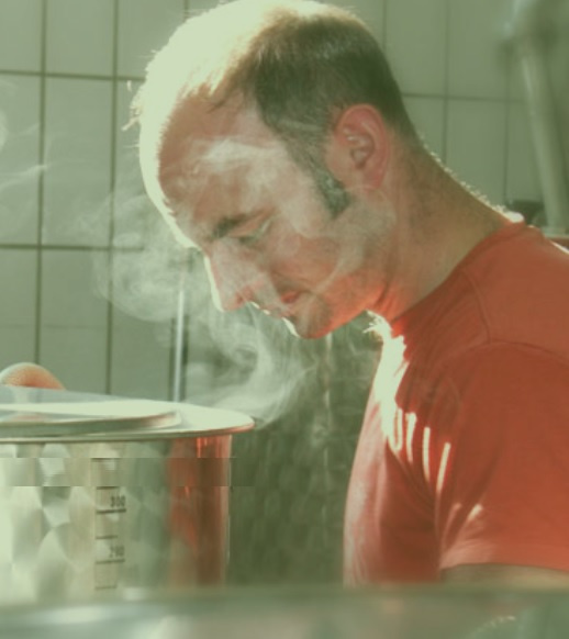 KI generiert: Ein Mann in einem roten Shirt schaut in einen dampfenden Topf.