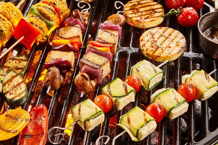 KI generiert: Verschiedene Gemüse- und Käse-Spieße auf einem Grill.