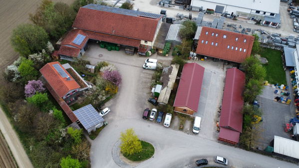 KI generiert: Luftaufnahme eines Hofes mit mehreren Gebäuden und Solarpanels auf den Dächern.
