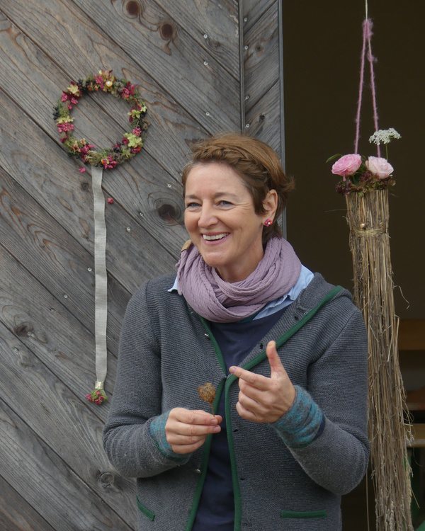 KI generiert: Eine Frau lächelt vor einer Holzwand mit Blumendekorationen.