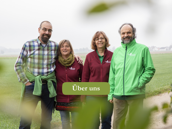 KI generiert: Vier Personen stehen lächelnd draußen. Der Text lautet: "Über uns".
