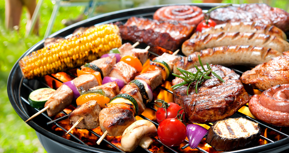 KI generiert: Verschiedene Grillgerichte, darunter Fleisch, Würstchen, Gemüsespieße und Maiskolben auf Holzkohlegrill.