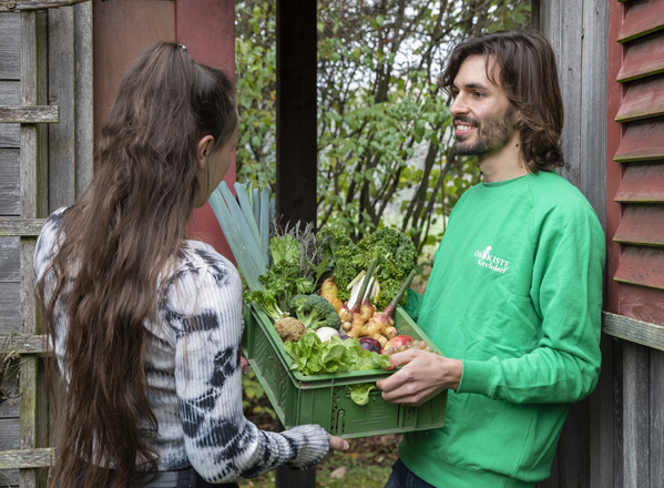 KI generiert: Personen tauschen eine Kiste frisches Gemüse aus.