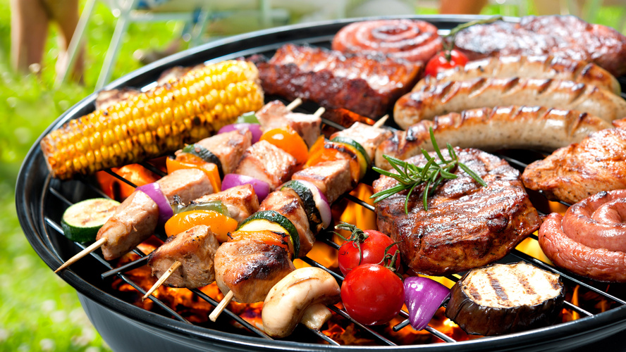 KI generiert: Ein Grill mit Fleisch, Würstchen, Mais, Gemüse und Spießen im Freien.